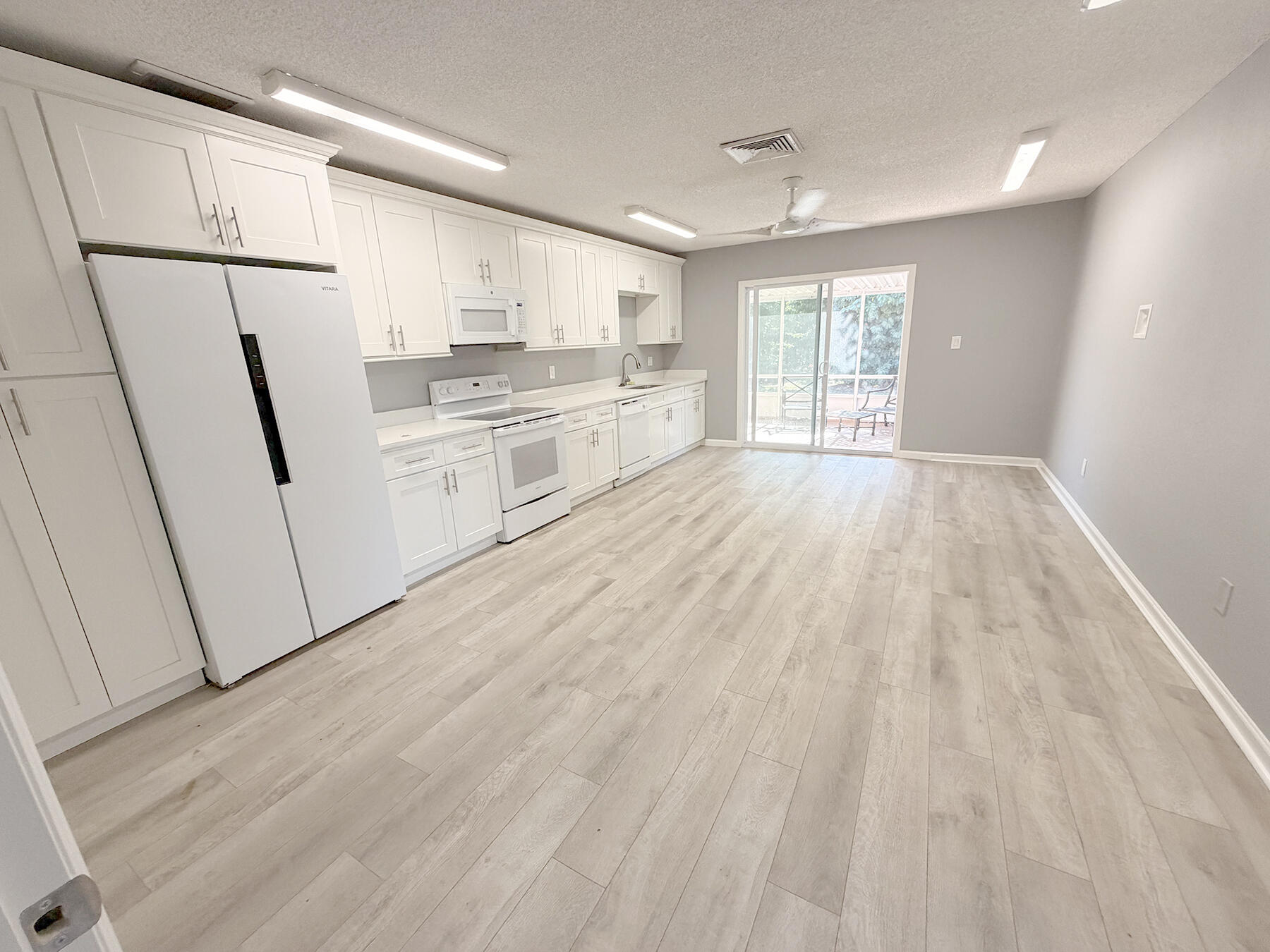 1902 Southeast Gena Road Port St. Lucie, FL 34952 - Photo 5 of 9 a large white kitchen with white cabinets and wooden floor