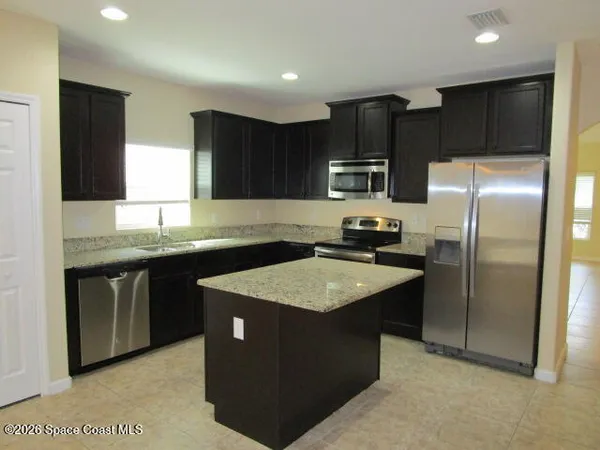 a kitchen with kitchen island granite countertop stainless steel appliances a sink stove and refrigerator