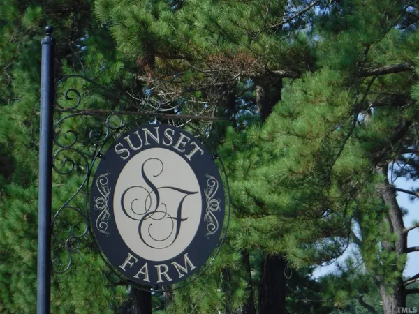 a view of sign board with yard and trees