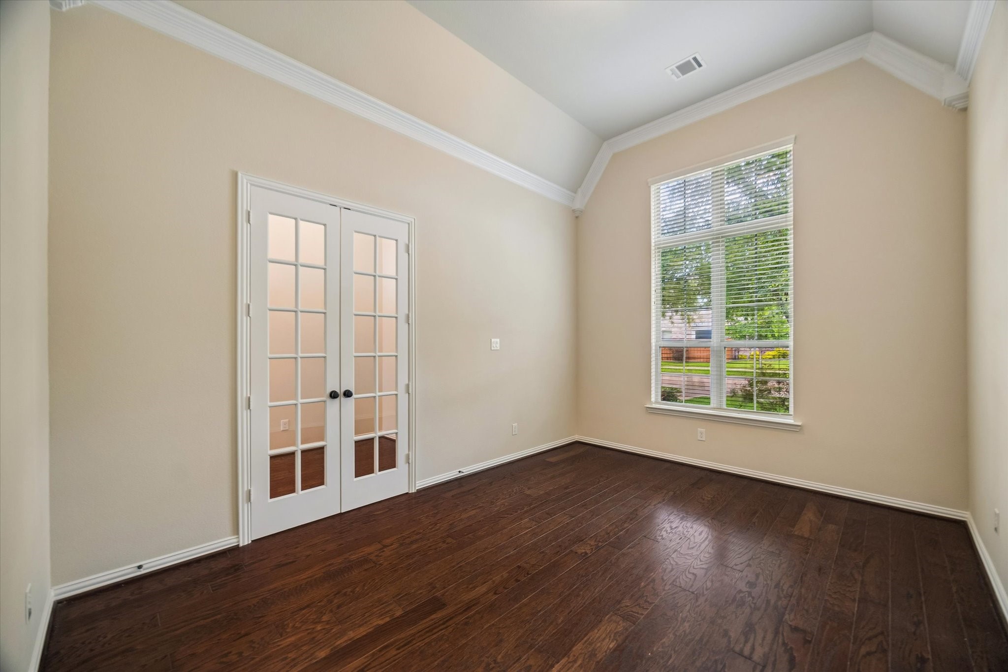 17403 Astrachan Road Richmond, TX 77407 - Photo 15 of 40 This room features rich hardwood floors, a large window with blinds for natural light, and French doors, offering a bright and inviting space perfect for an office or study.
