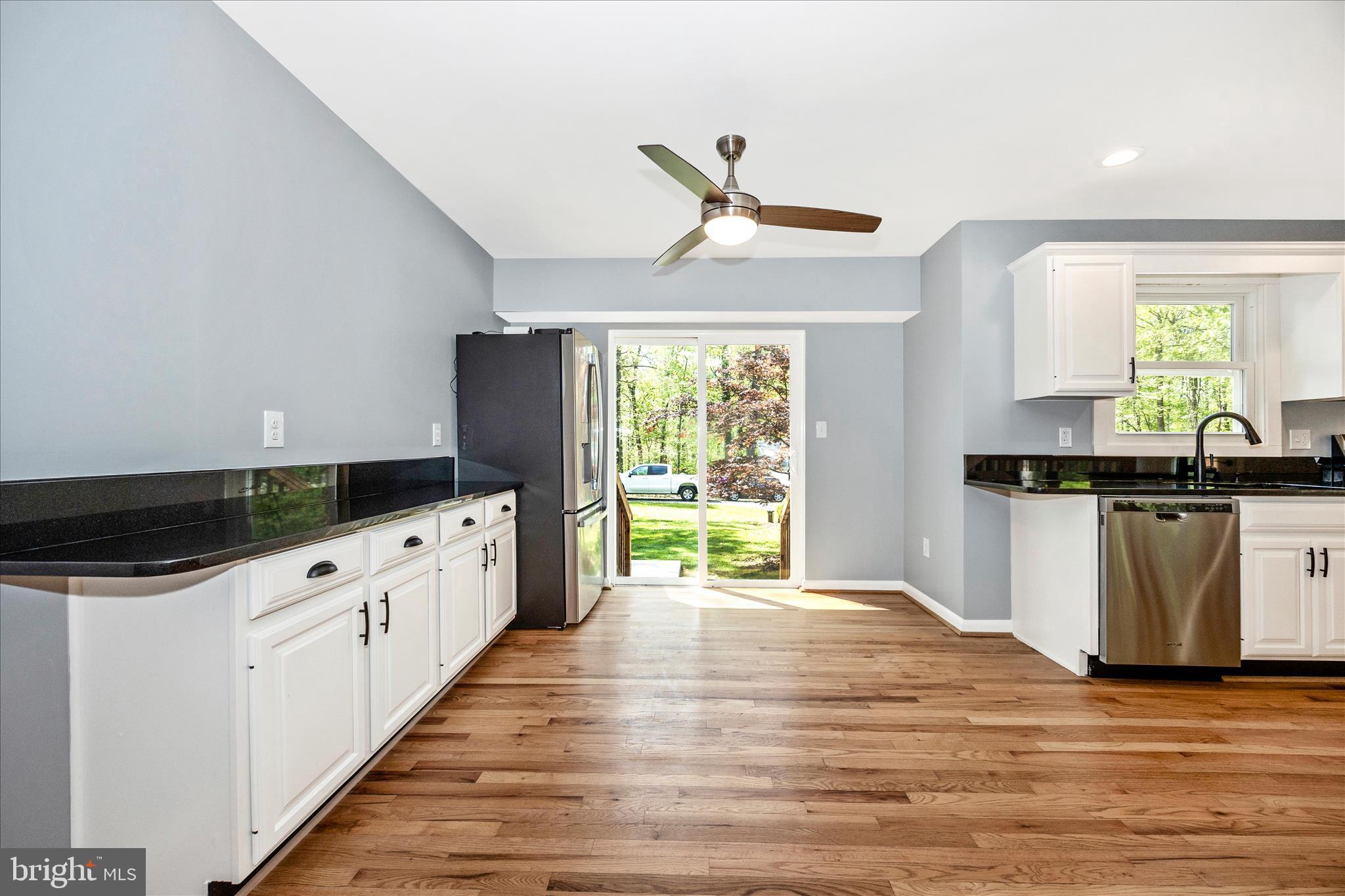 6518 Woodville Road Mount Airy, MD 21771 - Photo 15 of 53 a kitchen with granite countertop a white cabinets and wooden floor