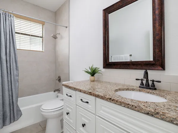 a bathroom with a granite countertop sink mirror vanity and toilet