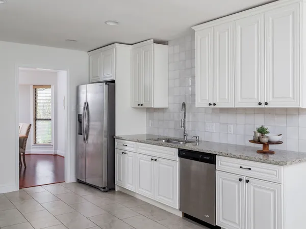 a kitchen with white cabinets and refrigerator