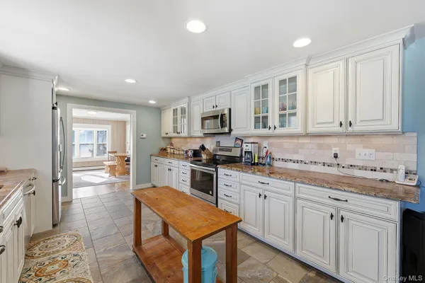 a kitchen with stainless steel appliances granite countertop a stove top oven a sink dishwasher and a refrigerator with wooden floor