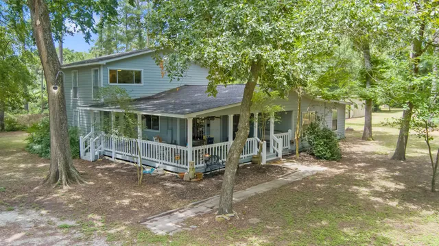 a view of a house with a yard and large tree