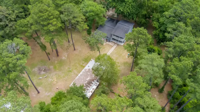 an aerial view of residential house with outdoor space and trees all around