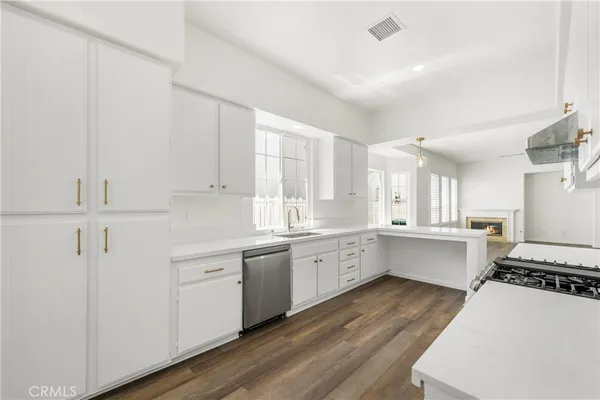 a large white kitchen with white cabinets and wooden floor