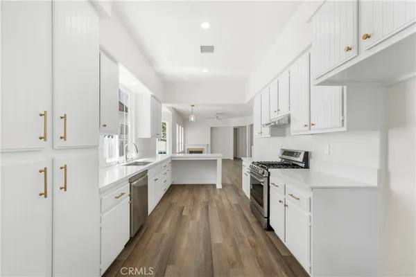 a large kitchen with stainless steel appliances sink a stove and cabinets