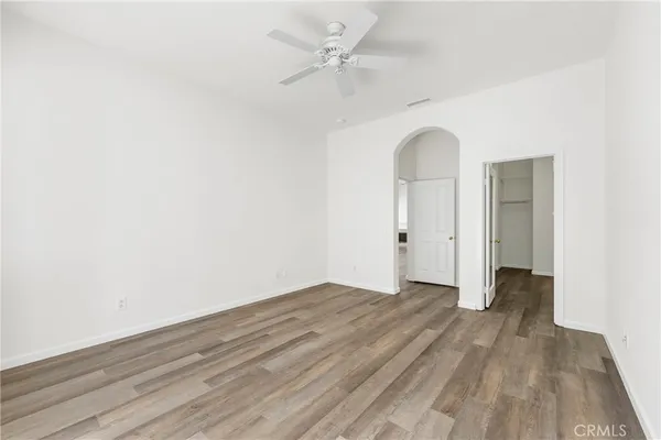 an empty room with wooden floor ceiling fan and windows