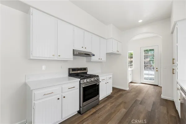 a kitchen with granite countertop white cabinets and stainless steel appliances