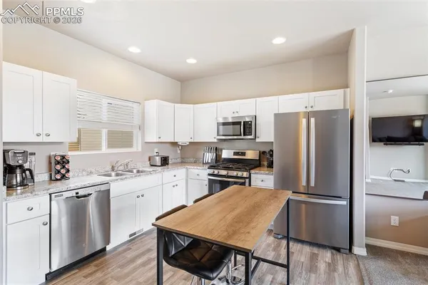 a kitchen with a refrigerator a sink dishwasher a stove and white cabinets with wooden floor