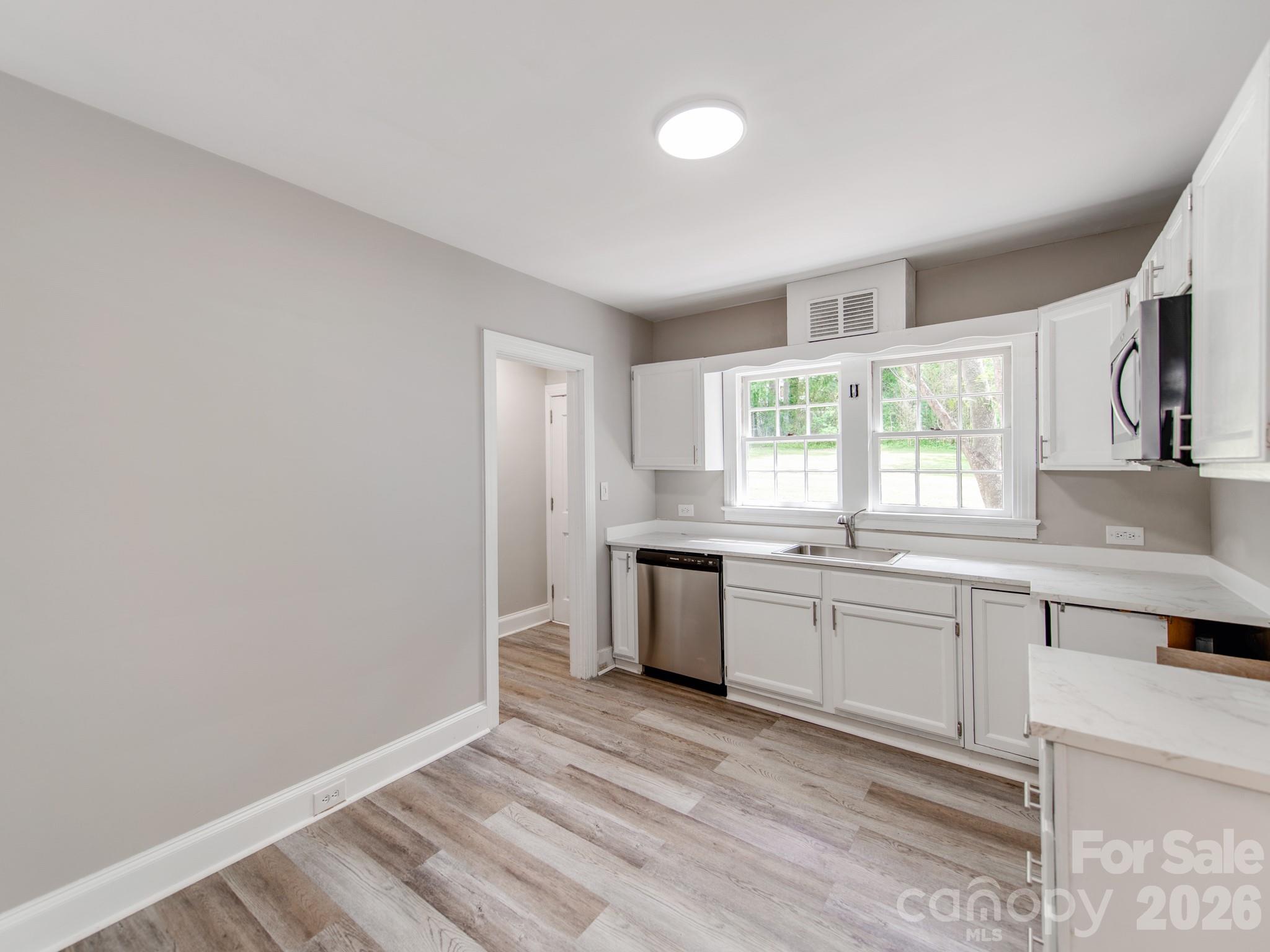 113 Falls Street Morganton, NC 28655 - Photo 9 of 33 a large white kitchen with granite countertop a stove a sink and dishwasher with wooden floor