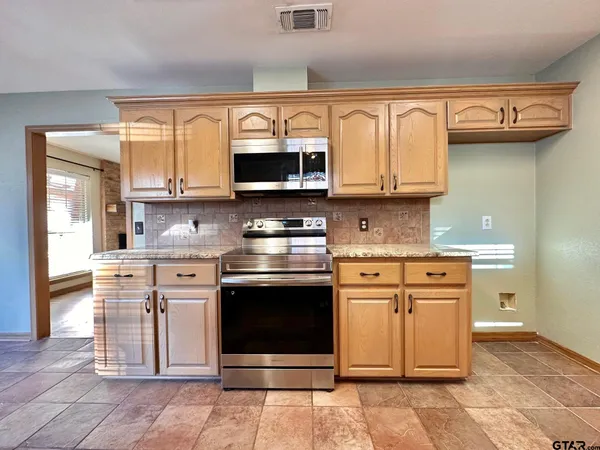 a kitchen with stainless steel appliances granite countertop a stove top oven microwave and cabinets