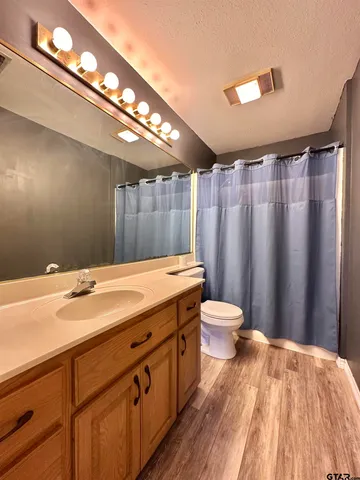 a bathroom with a granite countertop sink toilet a large mirror and a shower