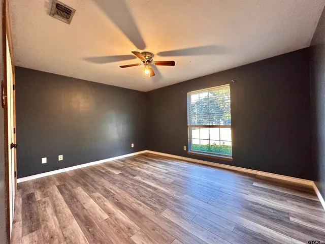 a view of empty room with wooden floor and fan