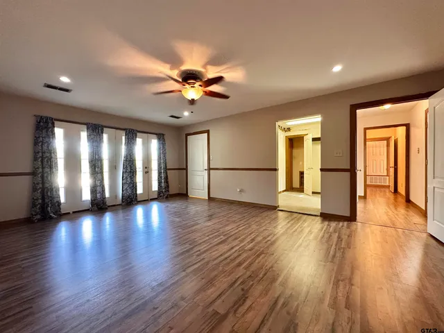 a view of an empty room with window and wooden floor
