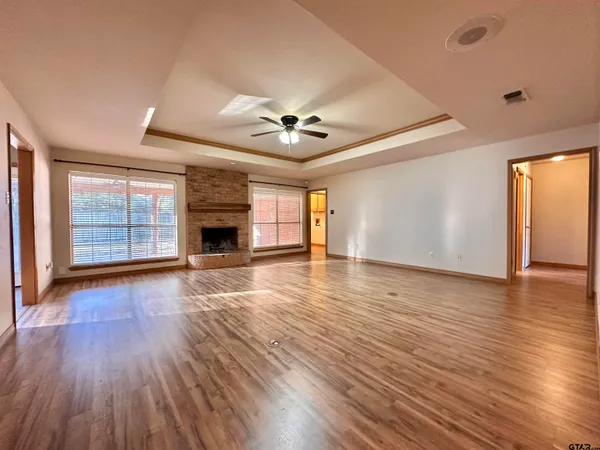 an empty room with wooden floor ceiling fan and windows