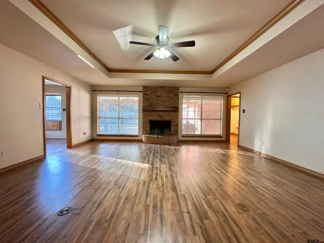an empty room with wooden floor fireplace and windows