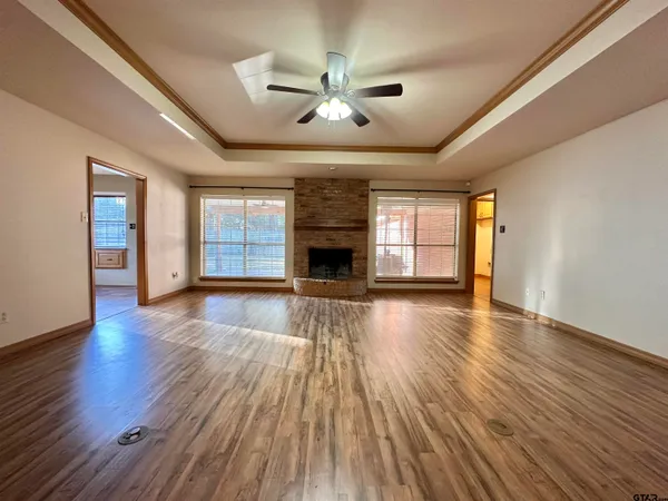 an empty room with wooden floor fireplace and windows