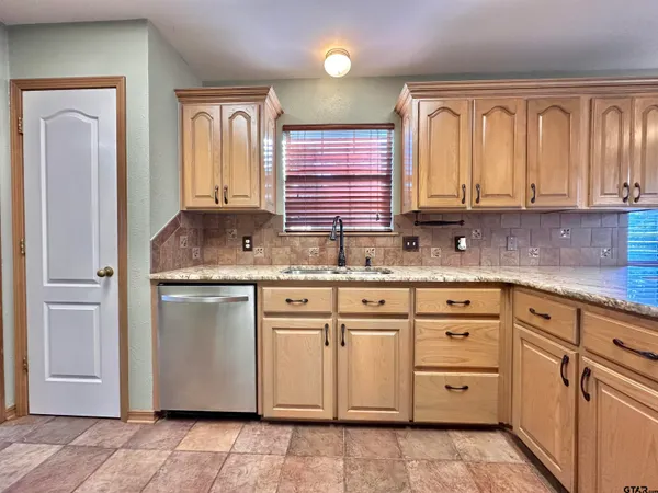 a kitchen with granite countertop white cabinets stainless steel appliances a sink and a window
