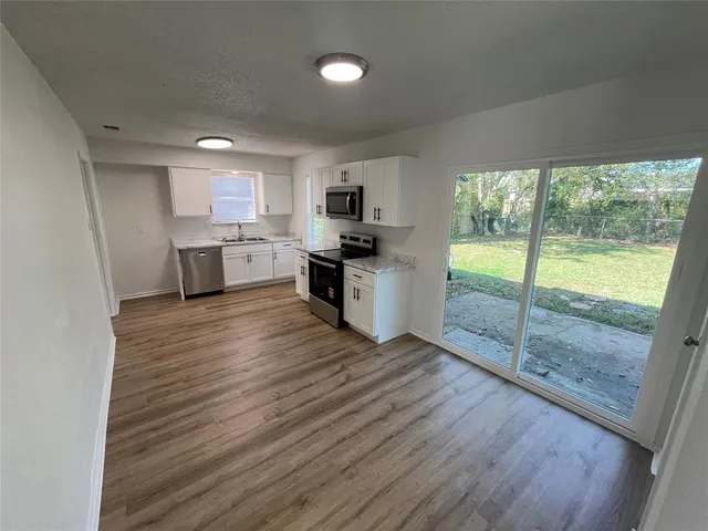 a kitchen with granite countertop a stove top oven a sink and a wooden floor