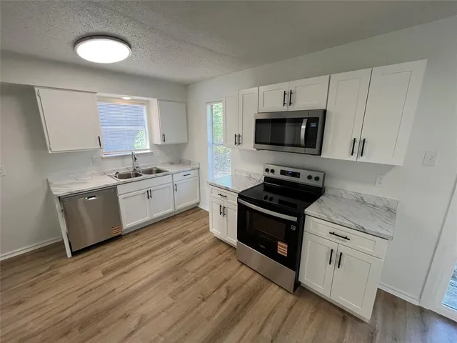 a kitchen with stainless steel appliances white cabinets and a stove top oven