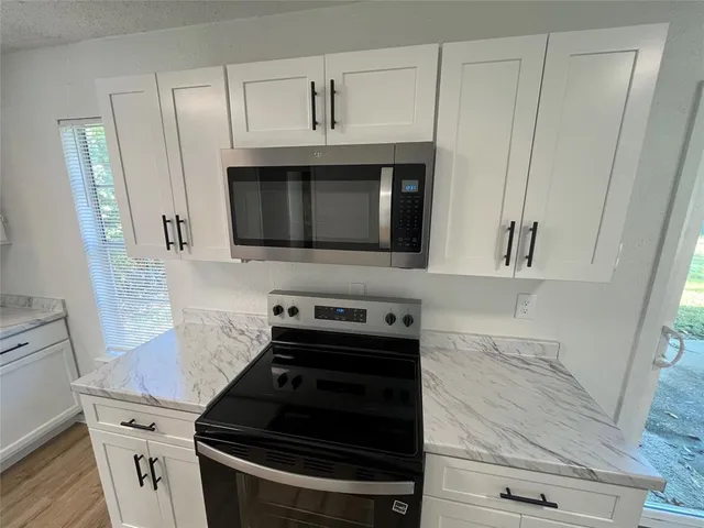a kitchen with granite countertop white cabinets and stainless steel appliances