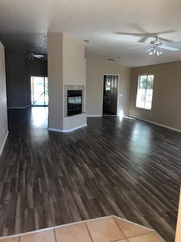 a view of an empty room with wooden floor and a fireplace