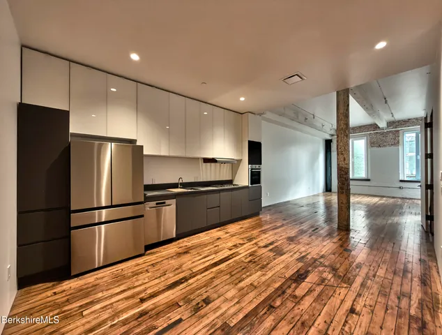 a kitchen with granite countertop a refrigerator and a stove top oven
