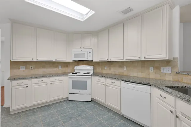 a kitchen with granite countertop white cabinets and white appliances