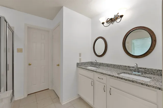 a bathroom with a granite countertop double vanity sink and a mirror