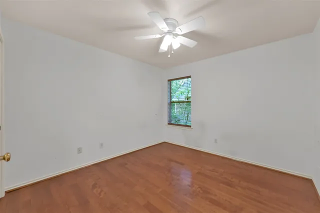 an empty room with a chandelier fan and windows