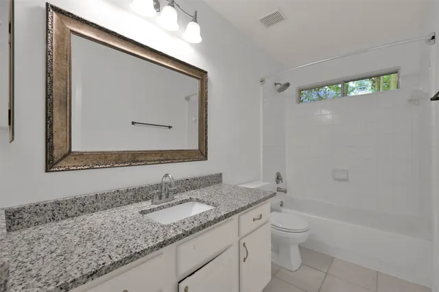 a bathroom with a granite countertop sink a toilet and a bathtub