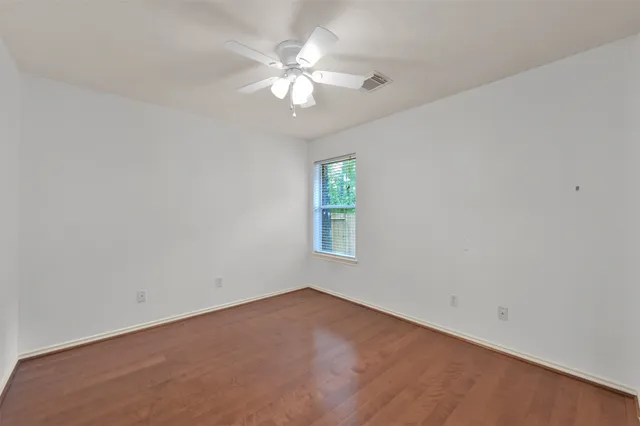 an empty room with a chandelier fan and windows