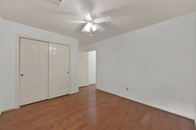 a view of an empty room with chandelier fan