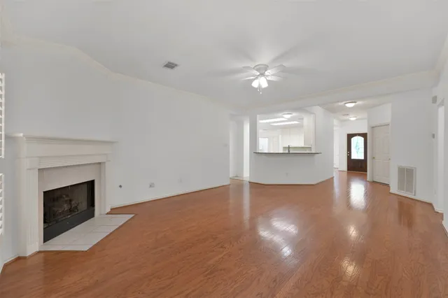 a view of an empty room with wooden floor and a fireplace