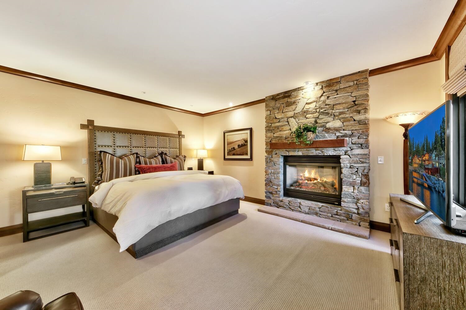6750 North Lake Boulevard, Unit 13F Tahoe Vista, CA 96148 - Photo 4 of 20 a spacious bedroom with a bed a flat screen tv and a fireplace with the outer view