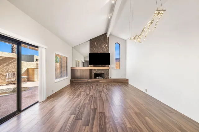 a view of an empty room with kitchen and wooden floor