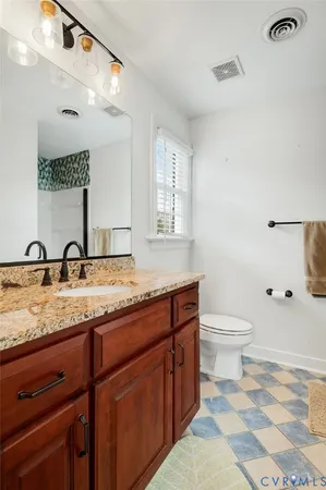 a bathroom with a granite countertop sink a toilet and a mirror