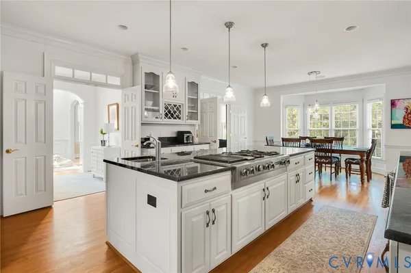 a kitchen with stainless steel appliances granite countertop a stove a sink dishwasher a refrigerator a dining table and chairs with wooden floor
