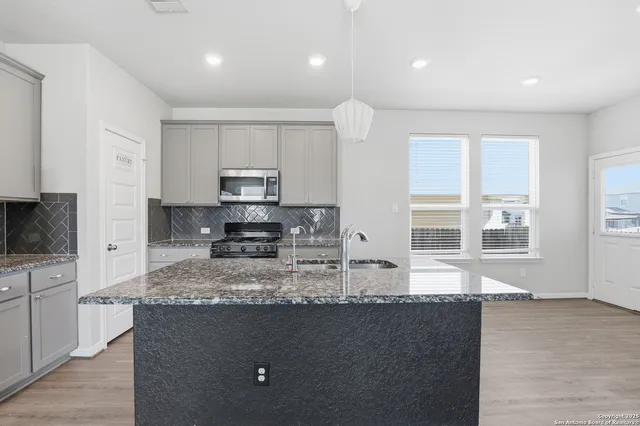 a kitchen with granite countertop a stove a sink a microwave a counter space and cabinets