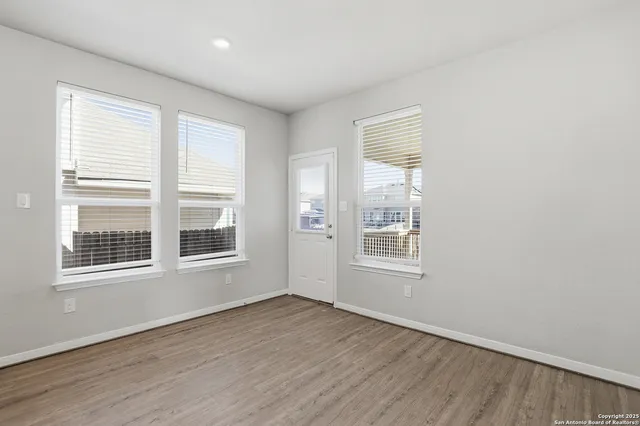 an empty room with wooden floor and windows