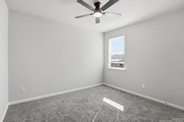 an empty room with a window and a fan
