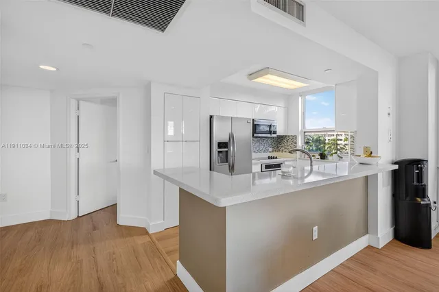 a kitchen with stainless steel appliances granite countertop a sink and a refrigerator