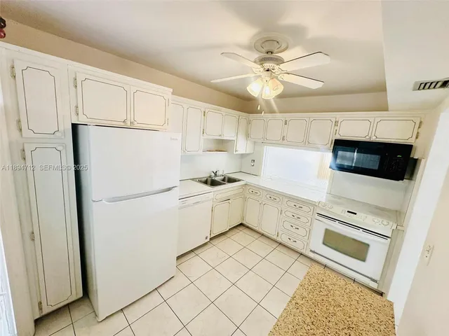 a kitchen with white cabinets and white appliances