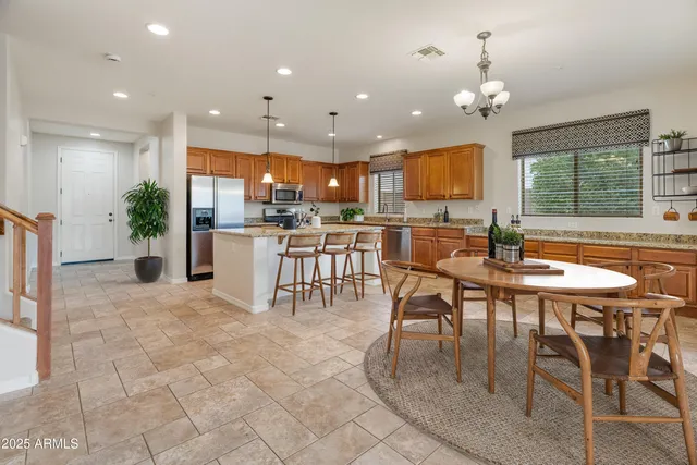a dining room with stainless steel appliances furniture a chandelier and kitchen view