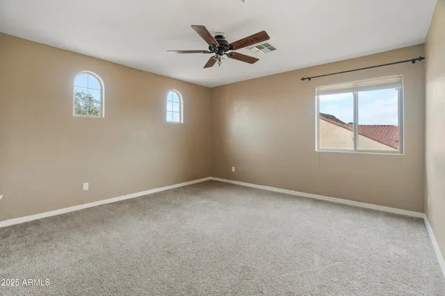 an empty room with a window and a ceiling fan