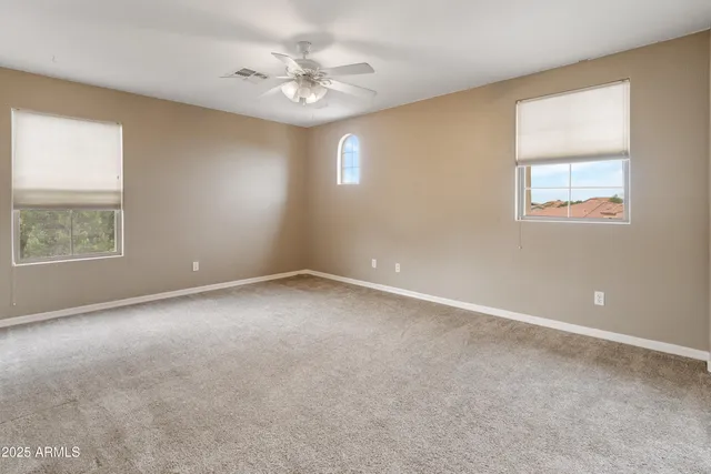 an empty room with windows and fan