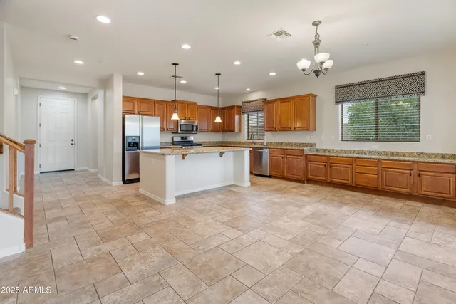 a large kitchen with kitchen island a sink a stove a dining table and chairs