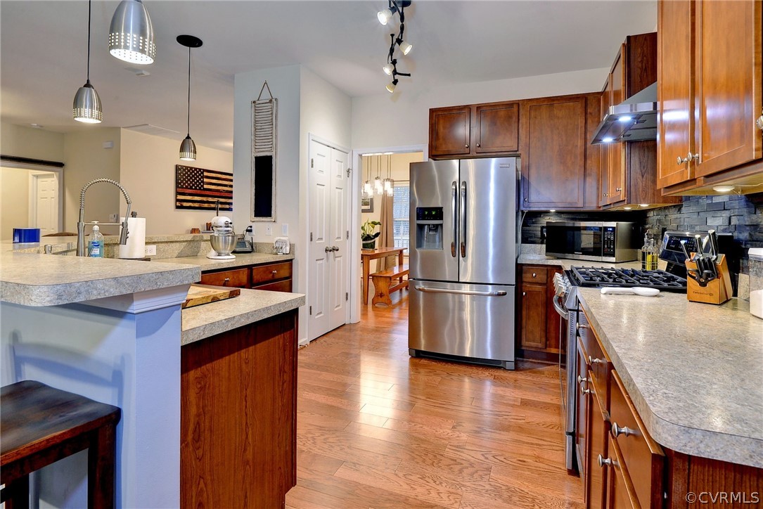8343 Patrick Henry Way Gloucester, VA 23061 - Photo 10 of 39 a kitchen with stainless steel appliances granite countertop a refrigerator a sink dishwasher a stove and a dining table with wooden floor